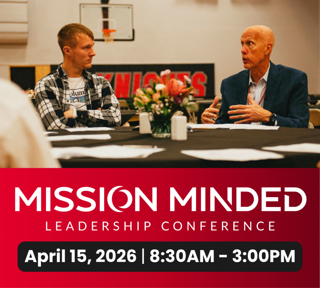 Two men sit at a table engaged in discussion at a leadership conference. Event details and date are displayed below: Mission Minded, April 15, 2026, 8:30AM–3:00PM.